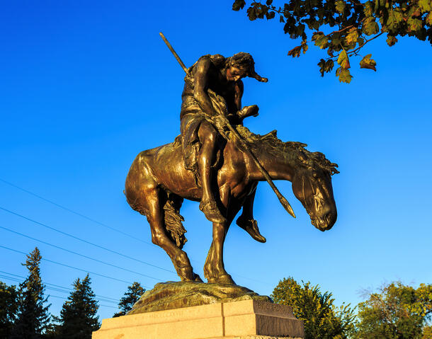 Equestrian sculpture of a Native American figure with spear slouched on a bowed, defeated horse.