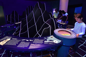 Visitors look into waist high displays that show seafloor images.