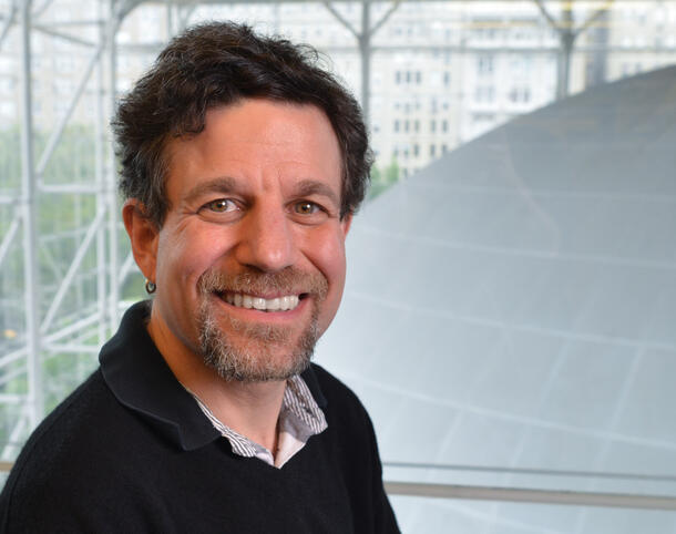 A man smiling at the camera with a dome, the Hayden Sphere, in the background.