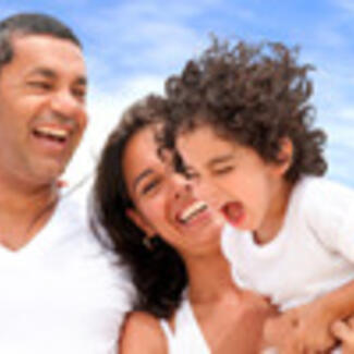 A photo of a man, woman, and child outdoors smiling beneath a blue sky.