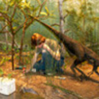 A person working in a diorama with a model of a therapod dinosaur with green vegetation in the background.