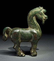 A horse figurine from China, dated 206 BC - AD 220. Of bronze, tarnished green, the horse has strong arched neck, a styled mane, and a stocky body.