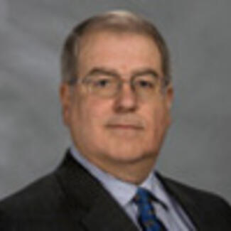 A bust-shot of man in a suit jacket and tie.