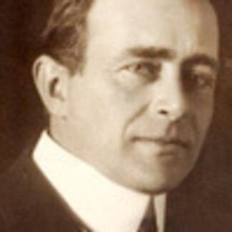 A black and white photograph of a man in an old-fashioned collar smiling at the camera.