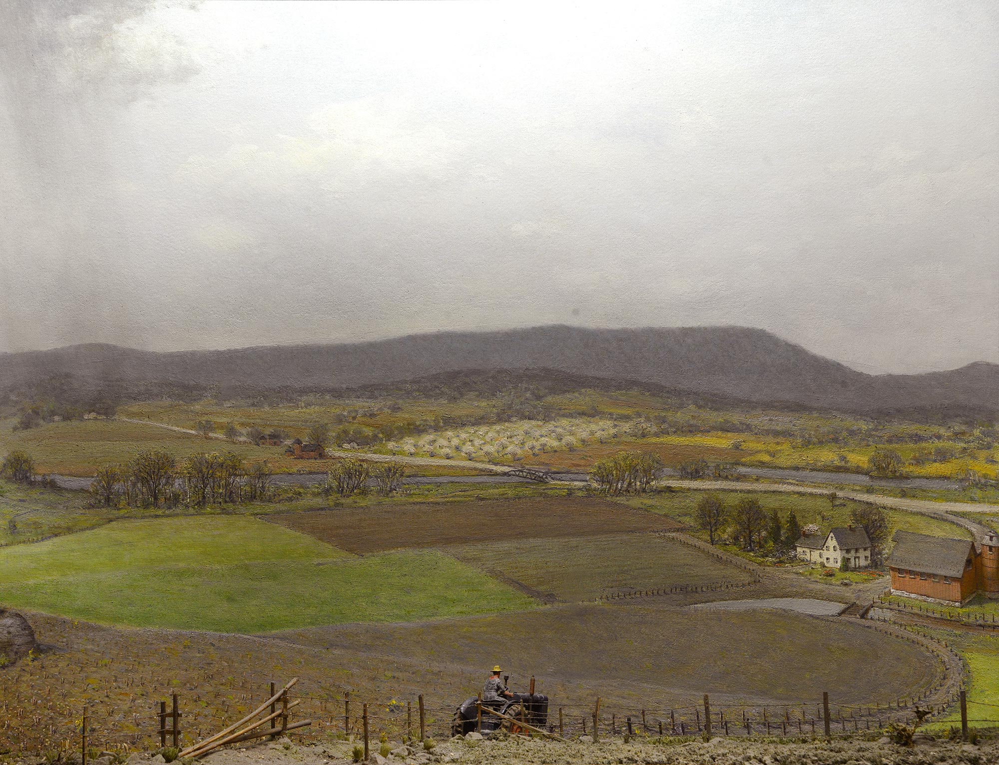 Diorama of a field and a farm in a cloudy day with a farmer on a tractor. 