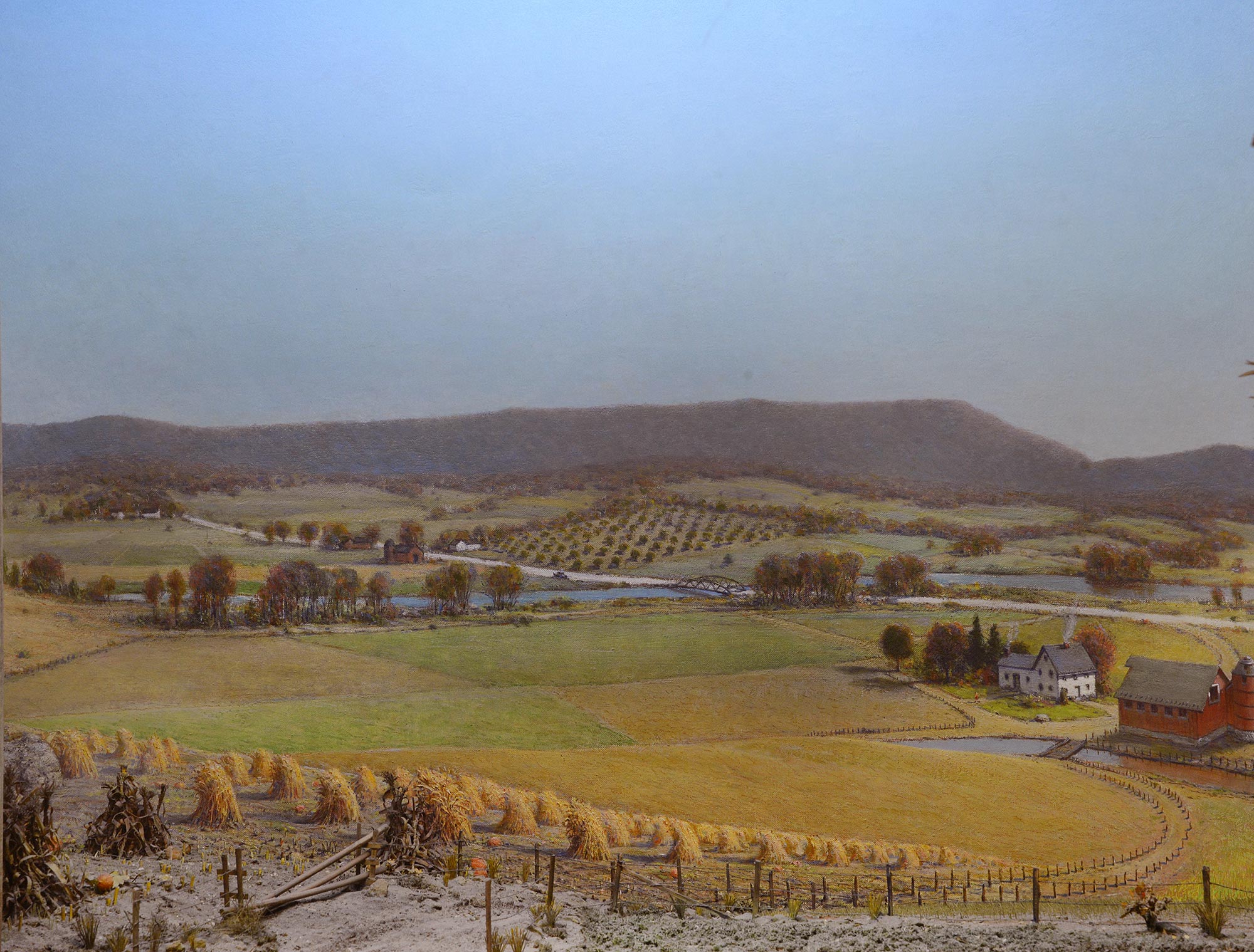 Diorama of a field and a farm in showing clear sky and yellowing fields. 