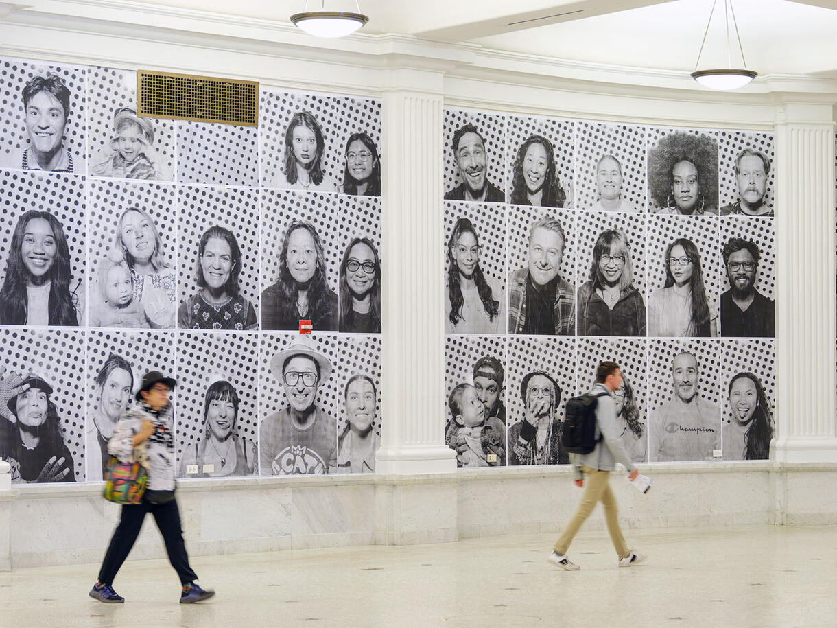 Museum visitors walk past the larger-than-life photographic portraits that are mounted on all of the walls within the Ellen Futter Gallery.
