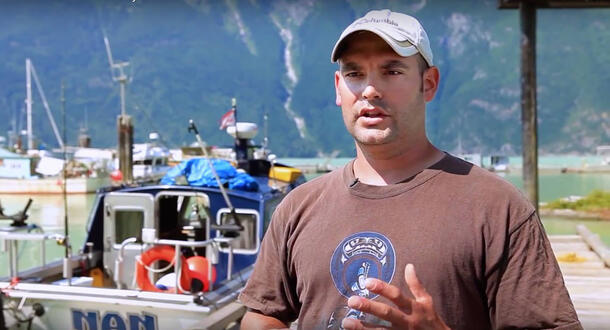 Jason Moody stands on a dock next to a fishing boat.