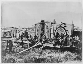 Black and white archival image showing people standing outside a house featuring circular designs painted on the front.