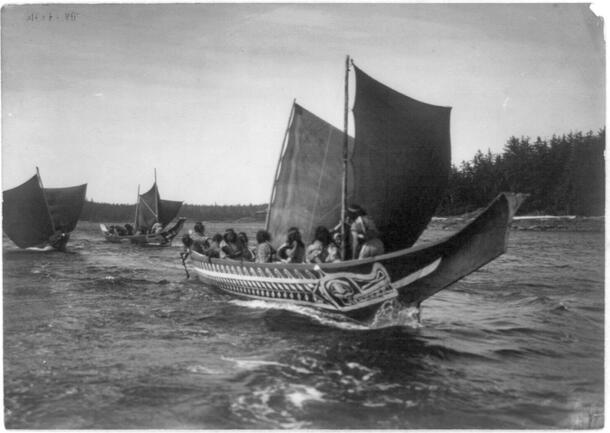 Archival image showing large wooden canoes with sails.