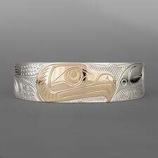 A silver bracelet features a rose gold raven's head in profile.