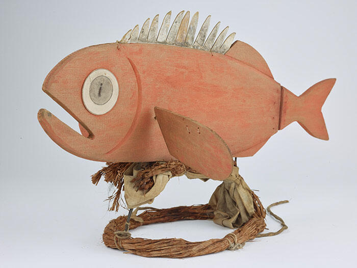 Hand-carved wooden fish is attached to a circular band that is worn as a headpiece.