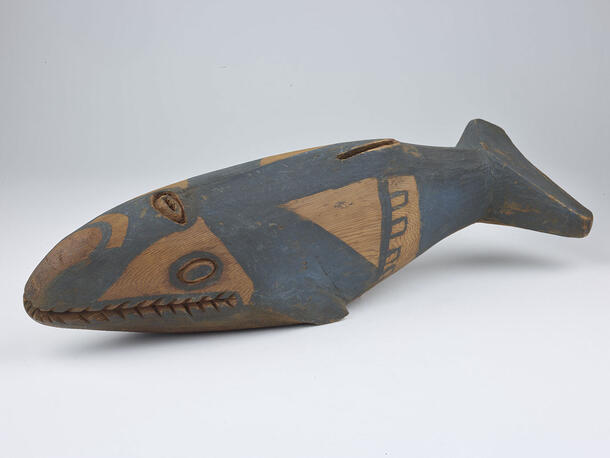 Carved and painted piece of wood in the shape of a whale.