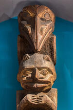 Carved wooden totem pole depicts a raven and a human and is located inside the Museum's Northwest Coast Hall.