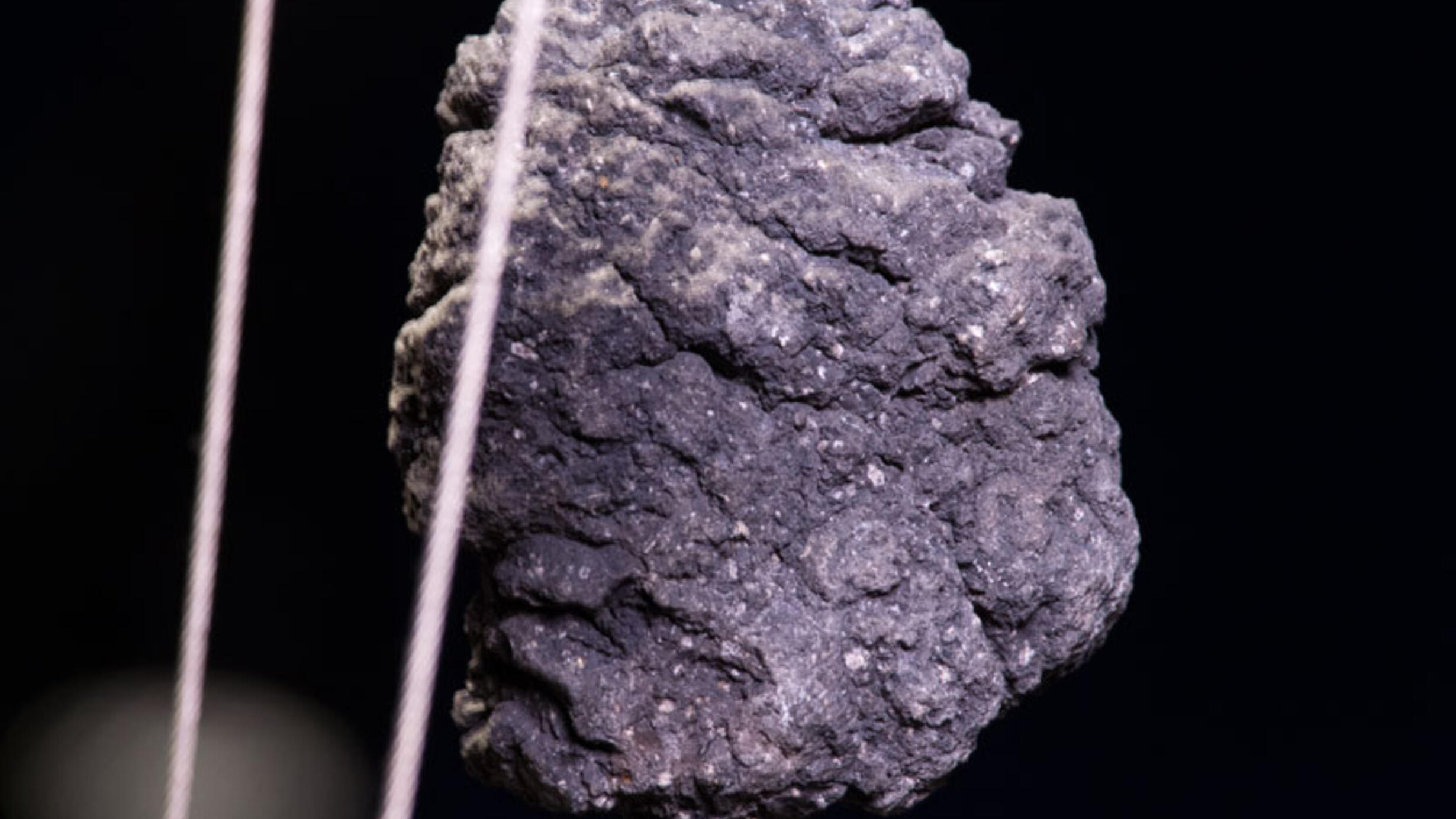 Two volcanic bomb specimens. These rocks form when blobs of magma projectiles cool. These two have round-oval shapes and bumpy irregular surfaces.