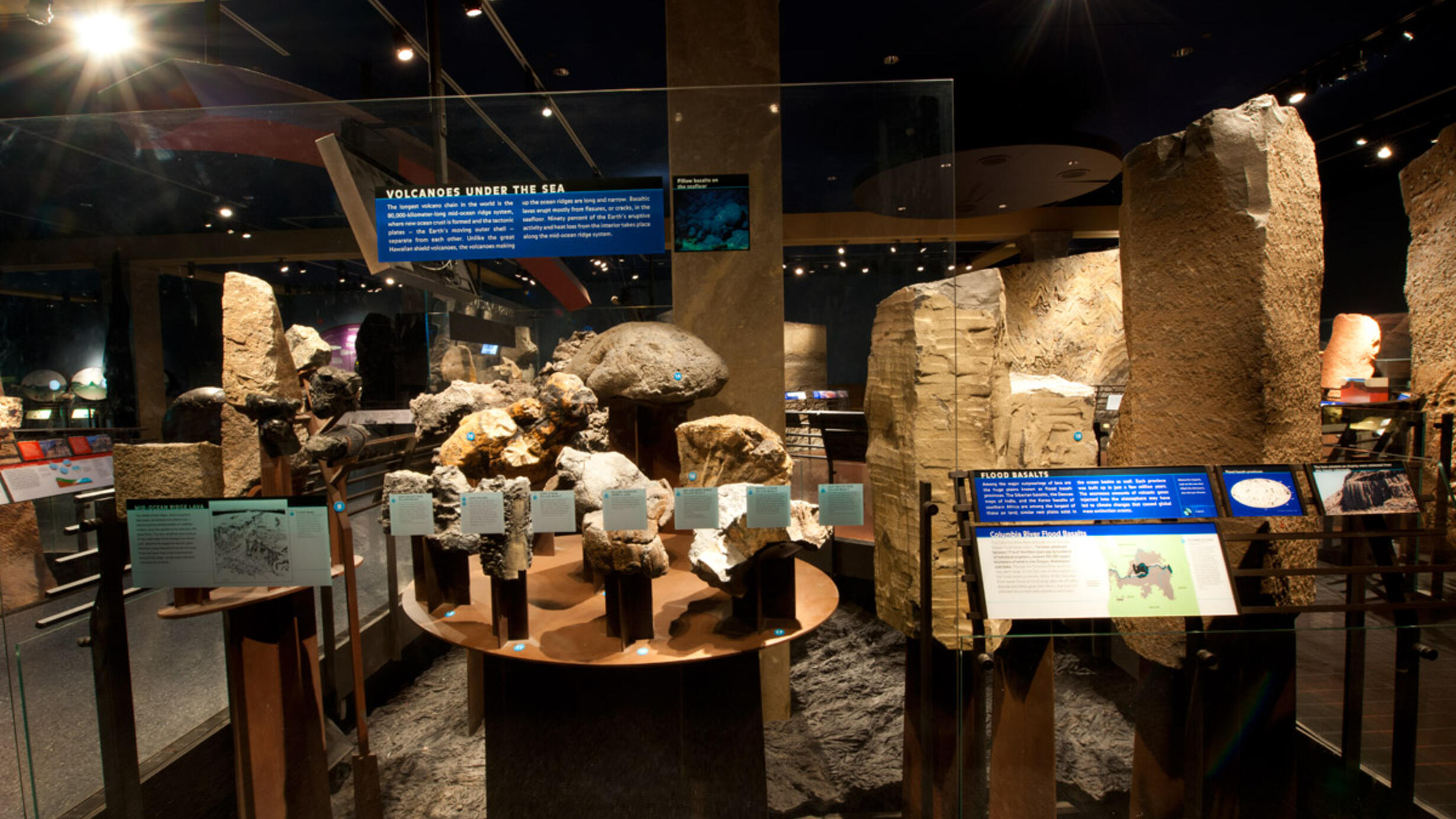 Rock specimens on display in the Hall of Planet Earth with text on a glass panel reading "Volcanoes Under the Sea." 