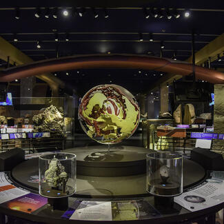 Museum's Hall of Planet Earth with the 3-D convection model at the center, flanked by displays of rock specimens and descriptive labels.