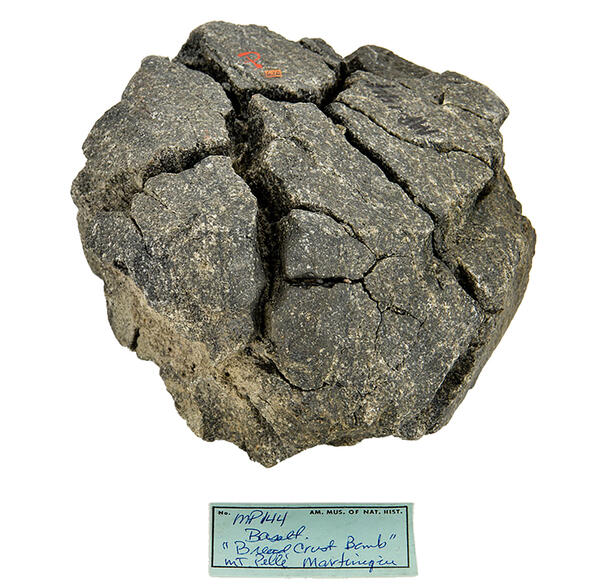 Volcanic rock specimen with identifying card reading, Basalt: "Bread Crust Bomb" Mt. Pelle Martinique.