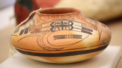 Round and low pot painted with geometric designs. 