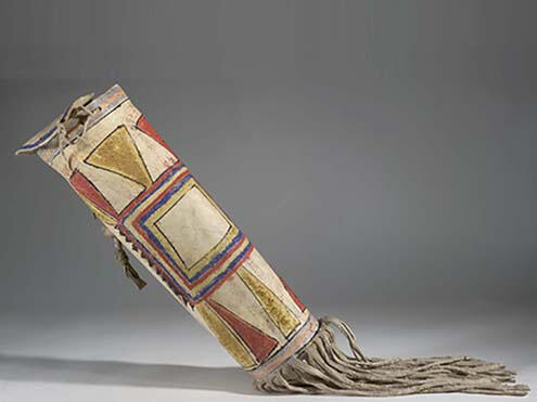 Small cylindrical bag made of hide with colorful geometric designs and tassels at the bottom. 