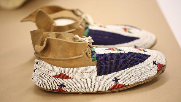 Pair of moccasins with colorful beaded designs covering the shoe from the ankle down to the toe. 