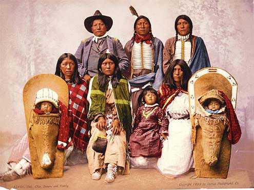 Family of nine, with two babies in cradleboards flanking five adults and one child posing in two rows.