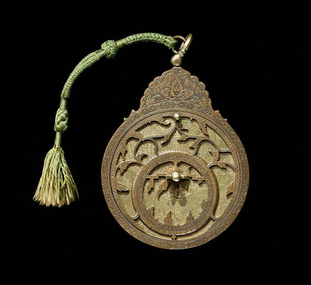 Circular bronze astronomical model sized to be handheld with intricate designs and a woven cloth handle.