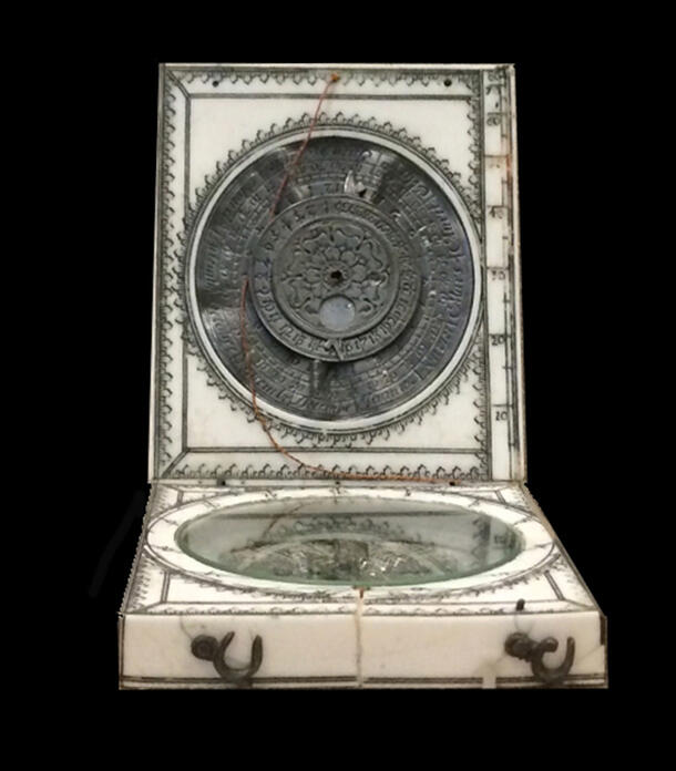 Ivory foldable sundial with an elaborate dial design with a flower at the center. 