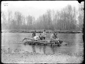 5 adults, a dog and pack on a wooden raft traveling down a river.