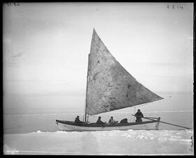 Five people on a sailboat on the icy sea.