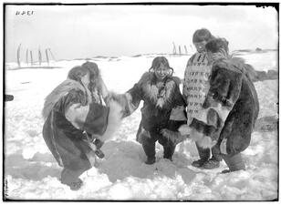Five women in thick, fur coats hold hands in a half-circle and dance in the snow.