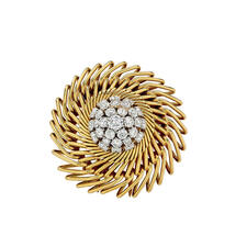 A clip with a diamond-studded core surrounded by three rows of rays made of gold.