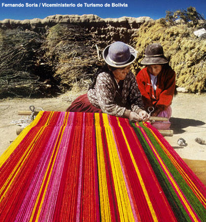 Two women weaving outside.