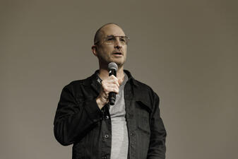 Director and Viktor producer Darren Aronofsky stands on stage with a microphone.