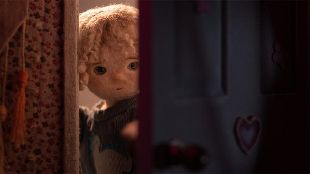A small, stop motion animated figure of 11-year-old protagonist Sam opening a door slightly and peeking through. 