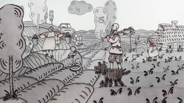 An embroidered scene of two adults, a child, and a dog in a farm field with a house and a car in the background.