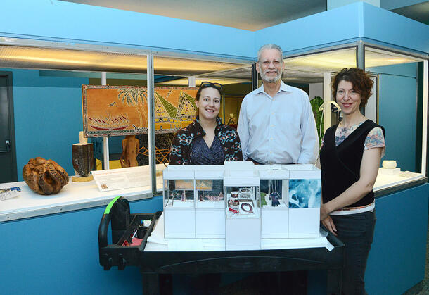 Three people stand beside a tabletop model of the new case.