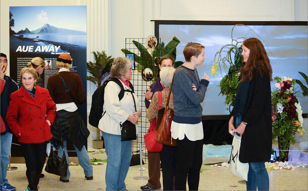Attendees view installation in the museum featuring poster, video and decorative elements.