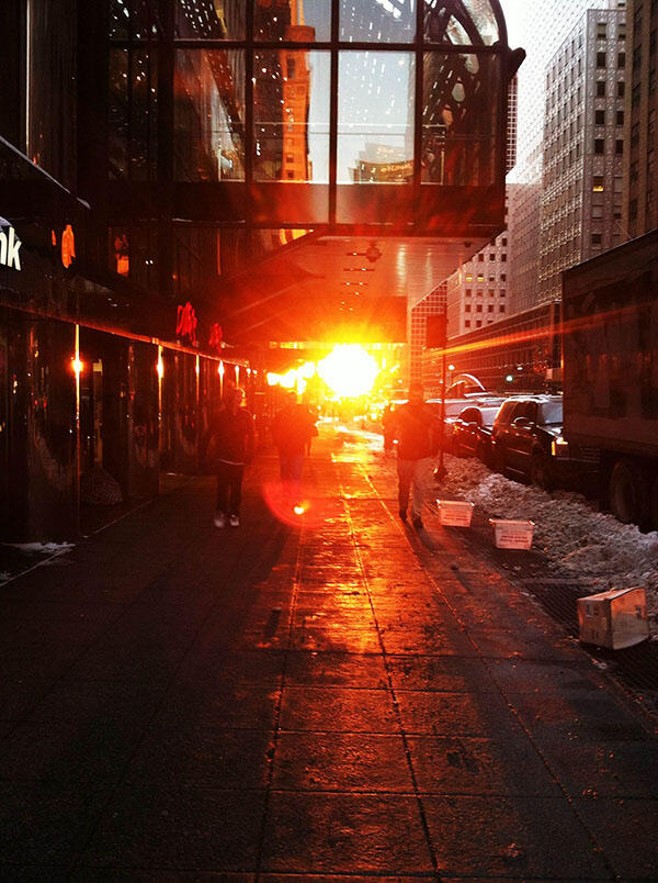 Sun shines at street level between tall office buildings.
