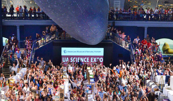 Aerial view of hundreds of students with cardboard kiosks displaying their science projects gather under the Museum's suspended blue whale model.