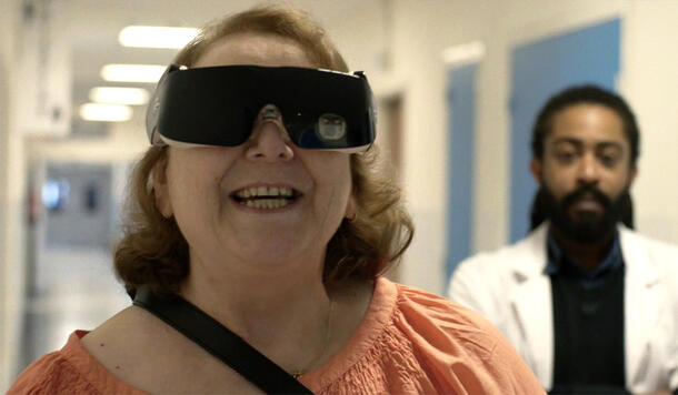 Smiling woman wears vision goggles while another person observes.
