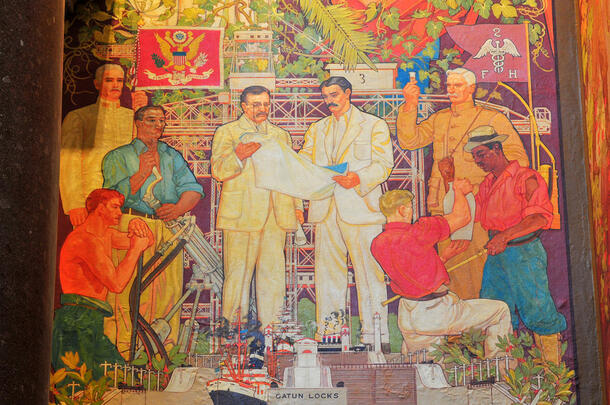 Colorful painted mural featuring Theodore Roosevelt and another man at the center, flanked by six more people including two in uniform. 