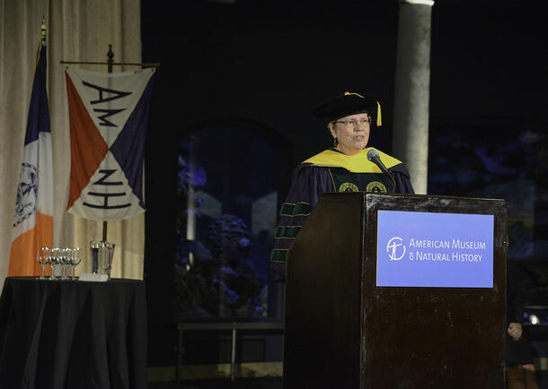 Marine biologist who received honorary degree stands at a podium to address graduates. 