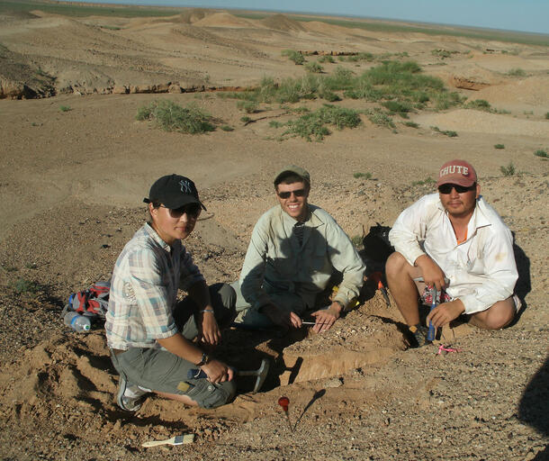 Danny Barta and two colleagues sit on the sand near an excavation site in the Gobi desert.