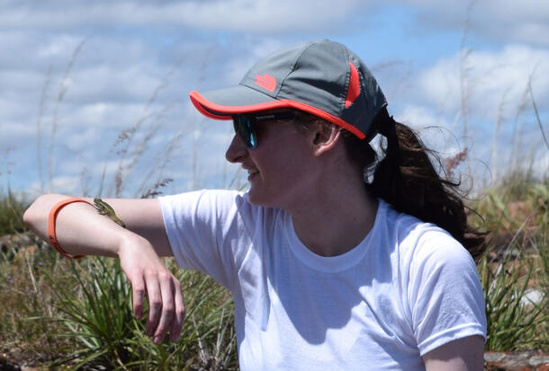 Rachel Welt holds her arm out to the side as a chameleon climbs on her arm.