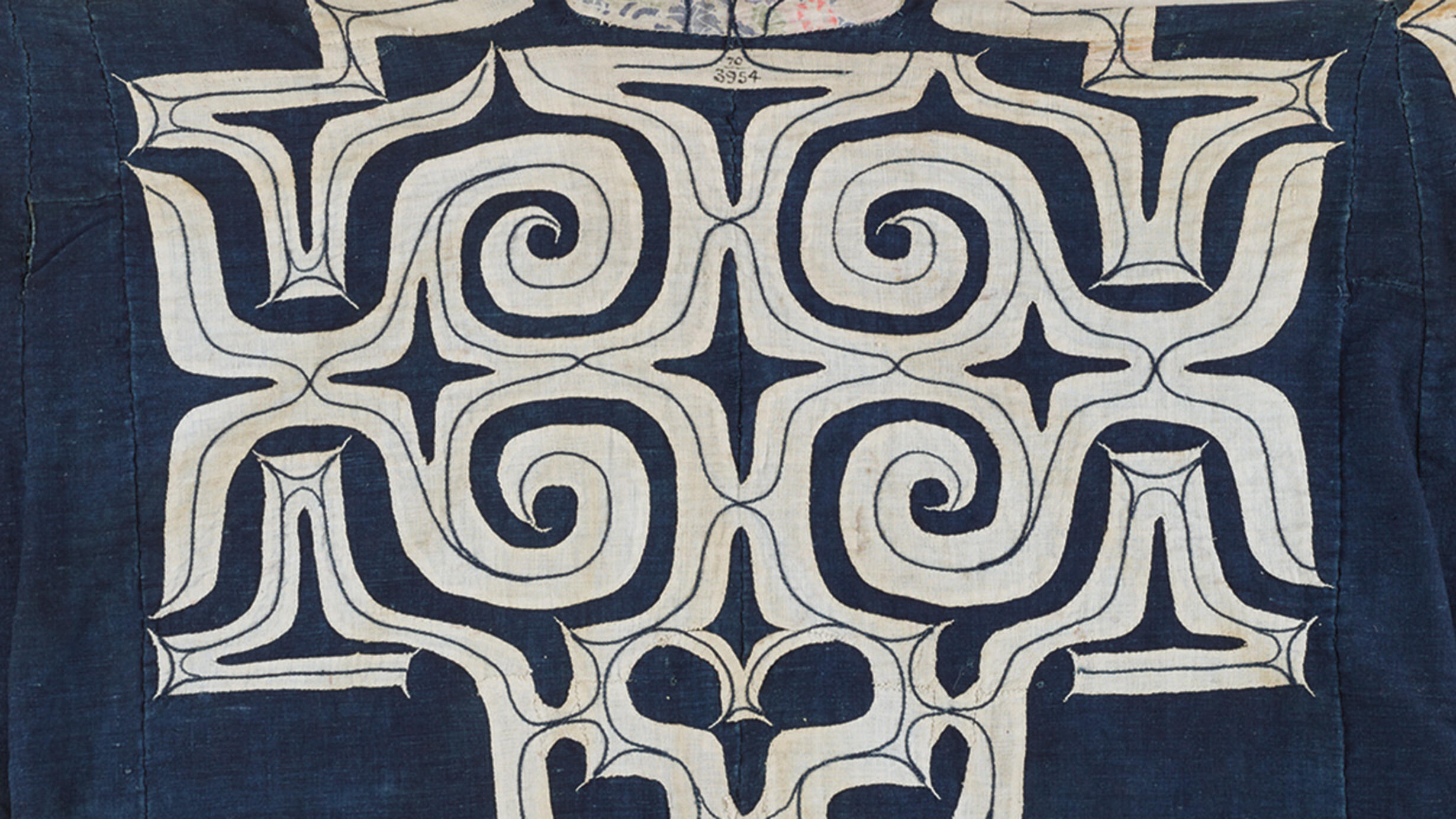 Detail of white applique patterning on a dark blue coat.