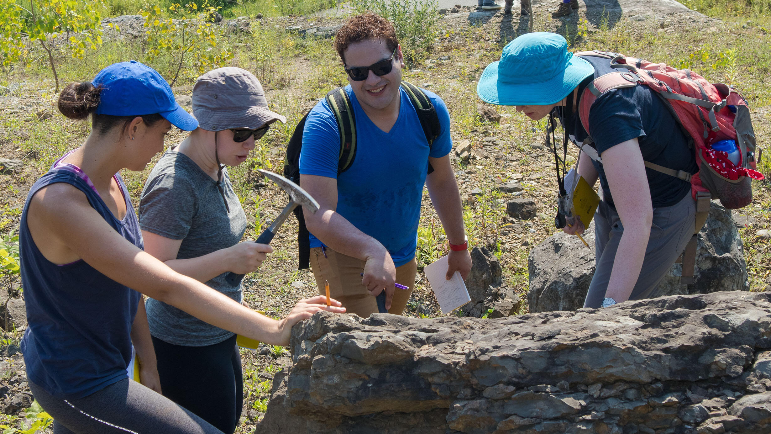 Earth science teachers from the MAT program examining a large rock. 