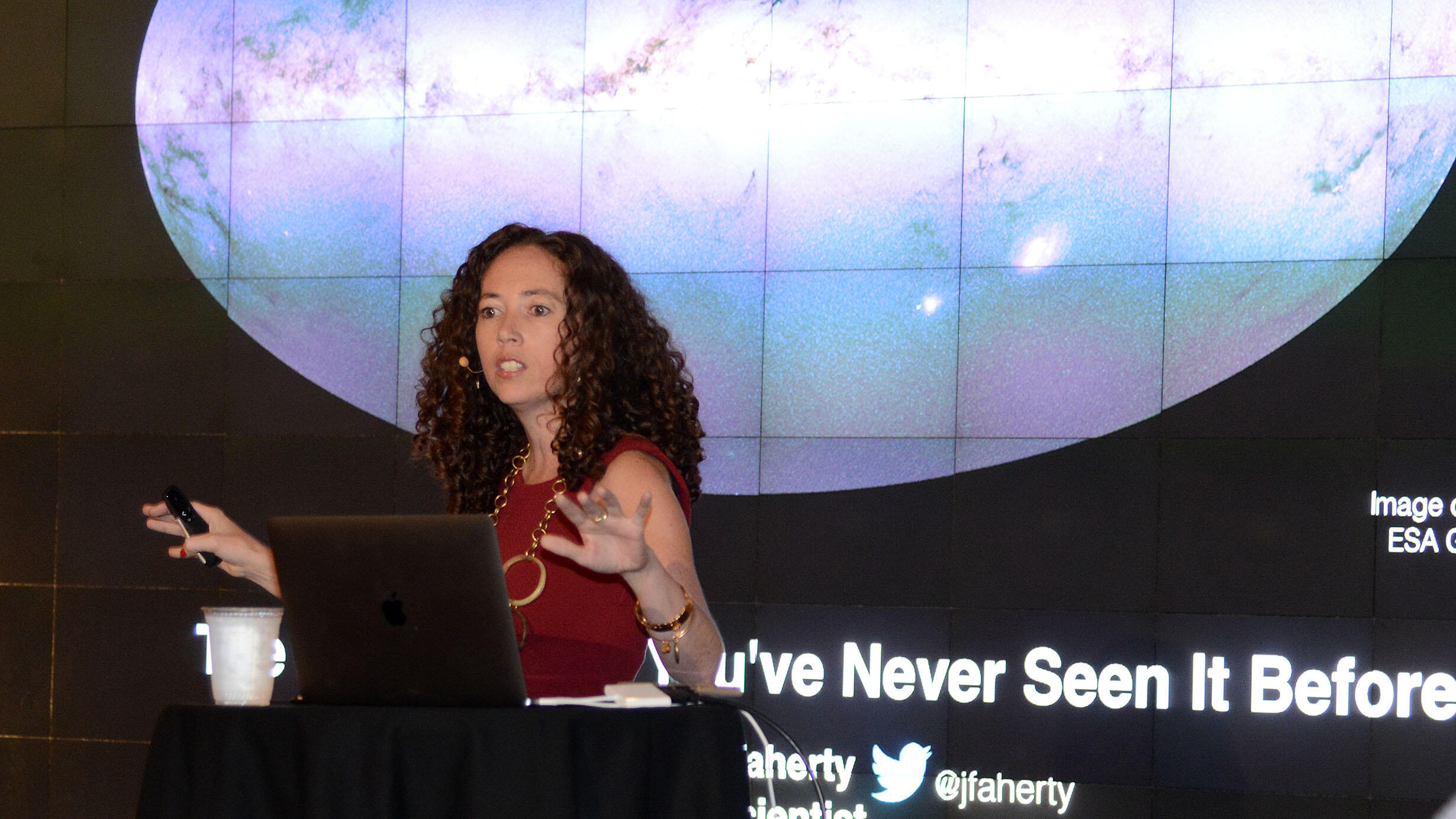 Jackie Faherty, Senior Scientist in the AMNH Astrophysics Department, stands at a podium giving a talk.