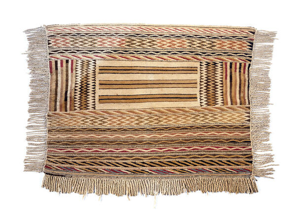 A woven blanket with varied patterns of slanted, jagged, and wavy lines and fringe on all four sides.