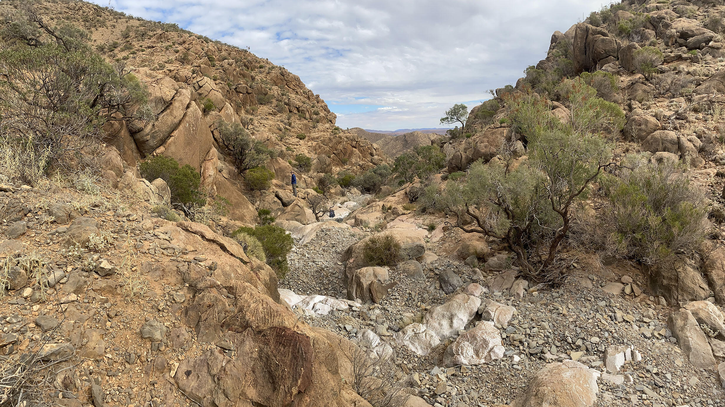 A person stands in the distance in a gap between rocky mountains in Australia. 